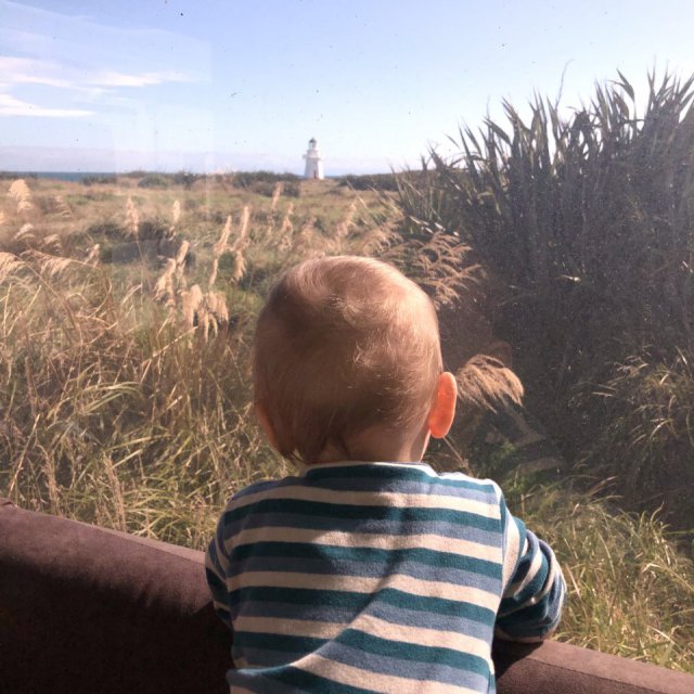 Baby schaut von Wohnmobil auf Leuchtturm